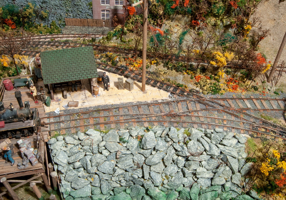 Hand-laid narrow gauge and standard gauge track cross on an O scale model railroad