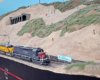 Three six-axle diesels in Southern Pacific, Union Pacific, and SP paint sit on siding in foreground as mountain rises in background. Rock shed near top of steep incline with more mountain above