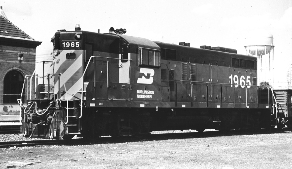 Black-and-white photo of four-axle road locomotive with high short hood