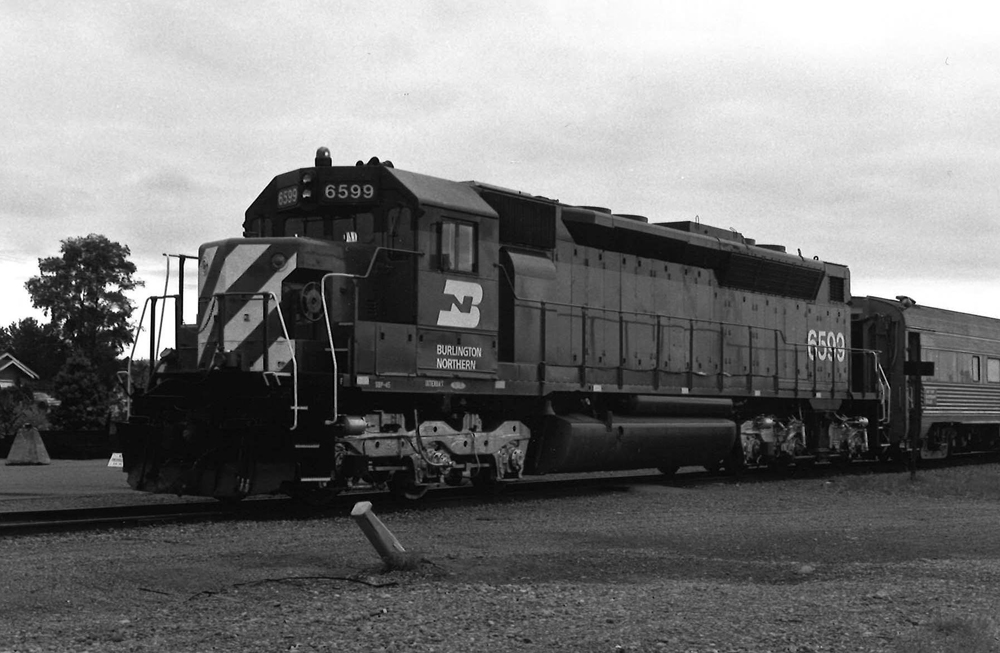 Black-and-white photo of six-axle road locomotive pulling fluted-side passenger car