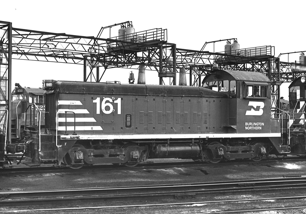 Black-and-white photo of end-cab switcher at diesel servicing track
