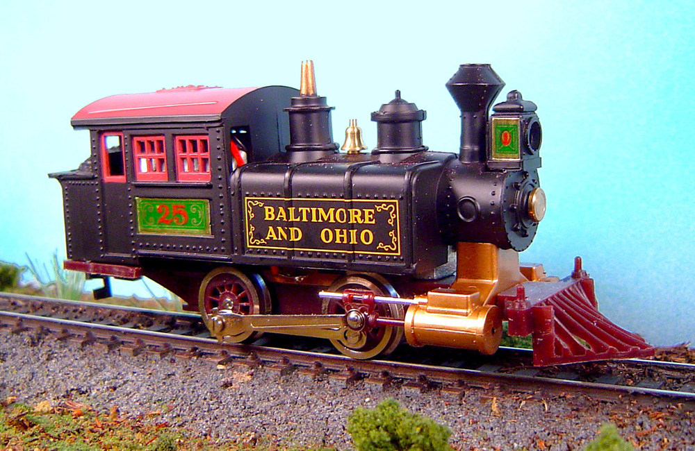 An HO scale 0-4-0 black saddle tank locomotive is seen on a landscaped track
