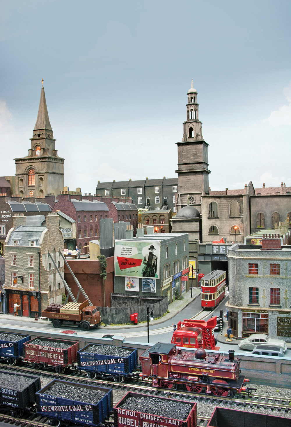 A switcher pulls coal cars while a tram travels on the street below.