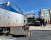 Black steam locomotive next to modern passenger diesel locomotive.