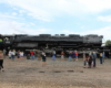 Side view of large black steam locomotive with a few people photographing it.