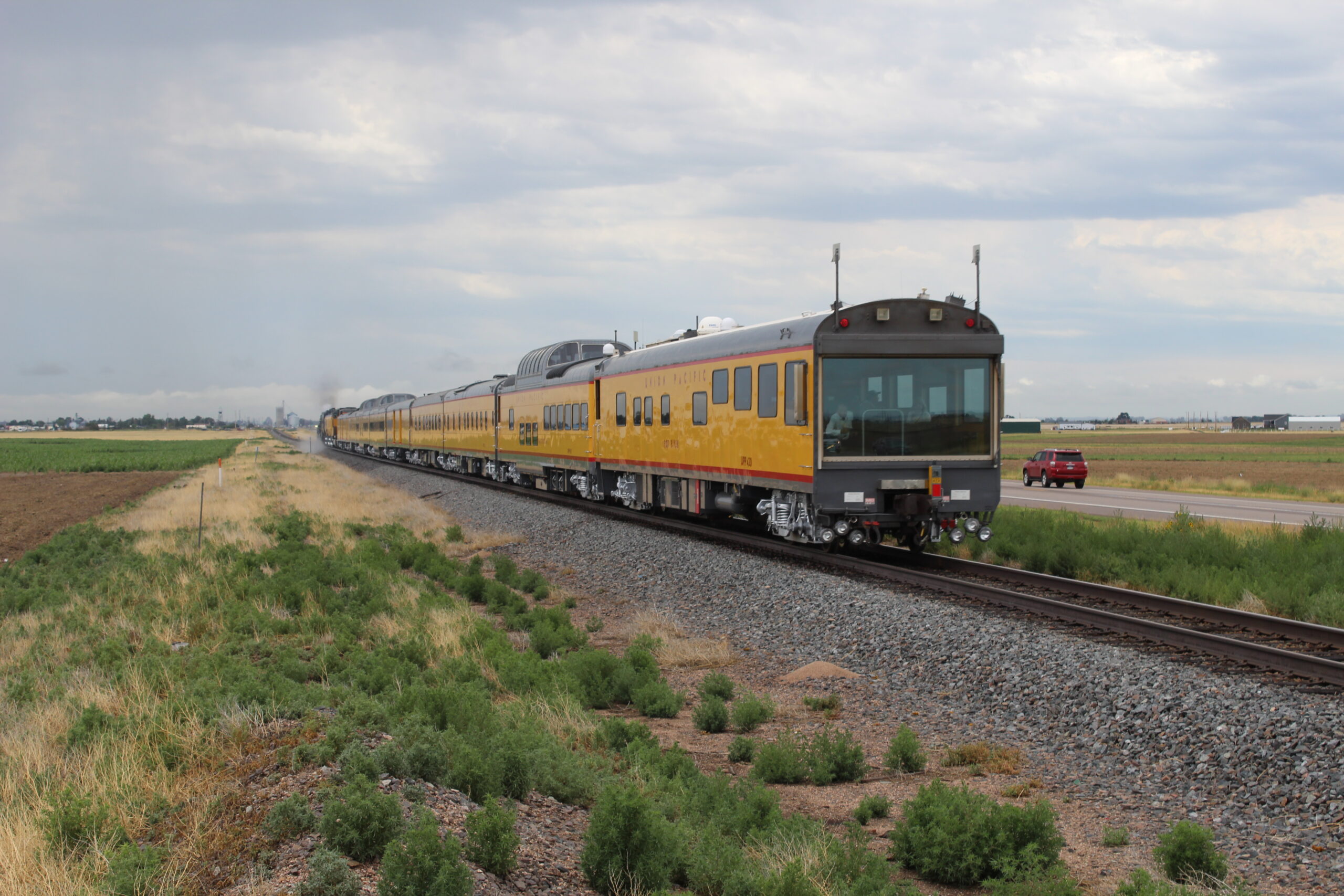 Yellow and gray passenger train traveling away from camera.