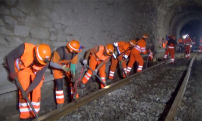 Workers moving a rail in a tunnel.
