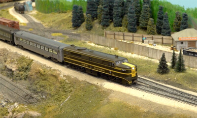 Brown model train engine heading a train on a layout.