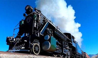 Close up image of a large steam locomotive under clear skies.