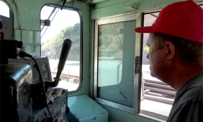 Locomotive engineer in hard hat in locomotive cab.