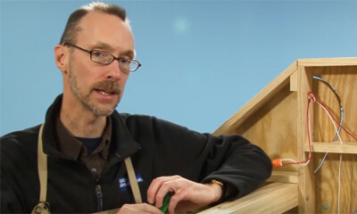 Man leaning against unfinished model train layout.