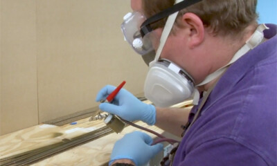 Man with safety gear spray painting a model train layout.