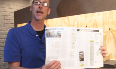 Man holding a magazine in front of an unfinished model train layout.