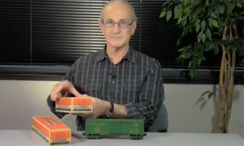 Man at a table holding a toy train box.