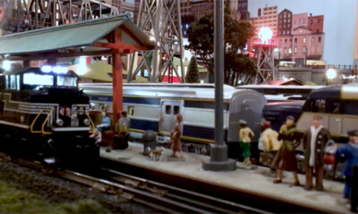 Multiple toy trains at a station platform.