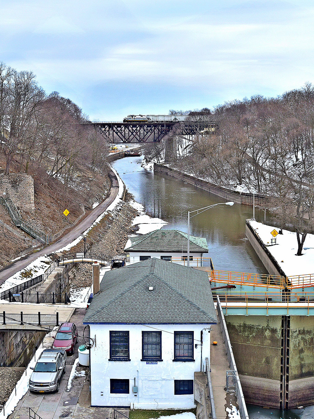 Freight train crosses bridge over a canal during winter.