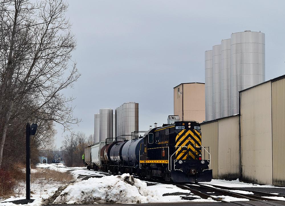 A black and yellow locomotive moves long-hood forward in a switching job.
