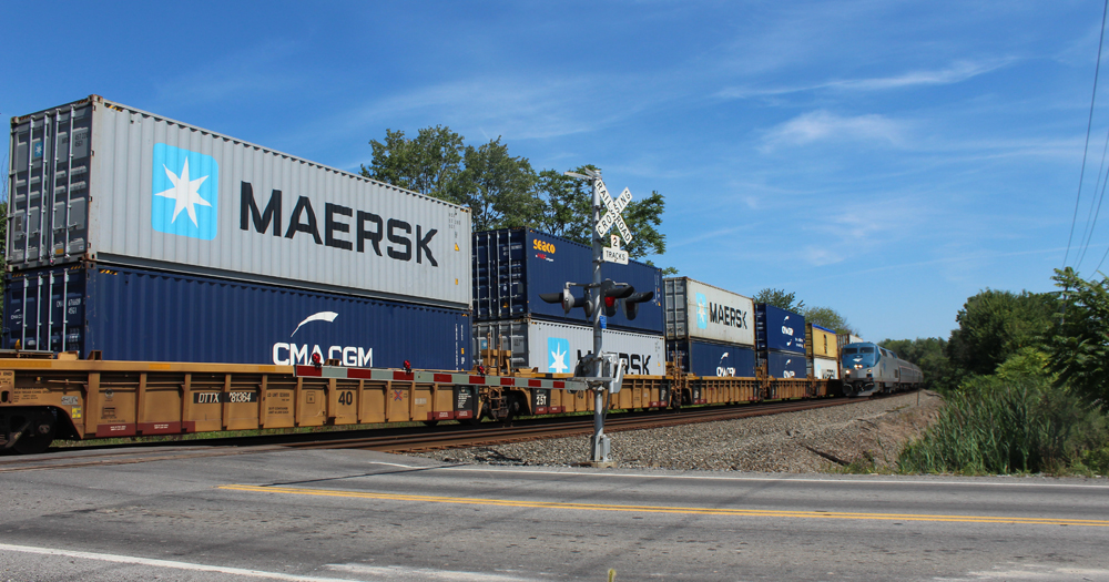 Passenger train approaches on track next to passing freight