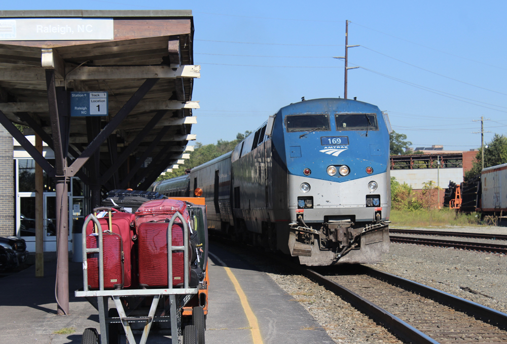Train arrives at station with baggage cart in foreground