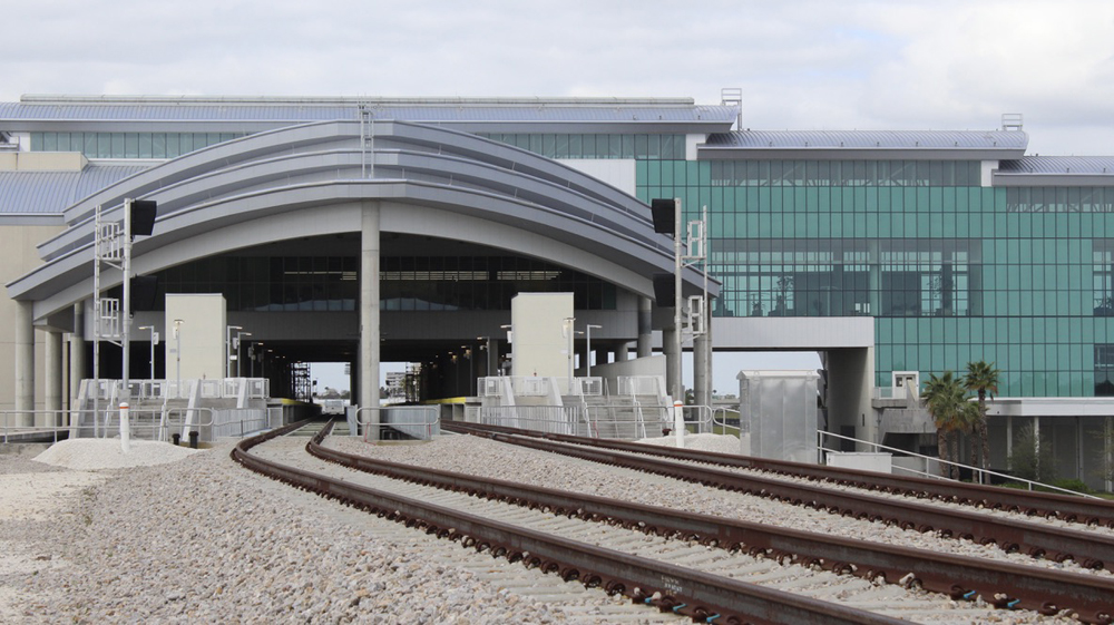 Railroad tracks lead into glass and concrete building