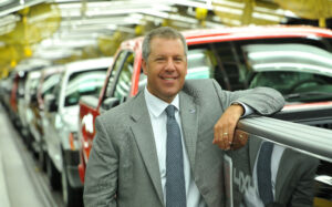 Man leading against vehicle at auto assembly plant