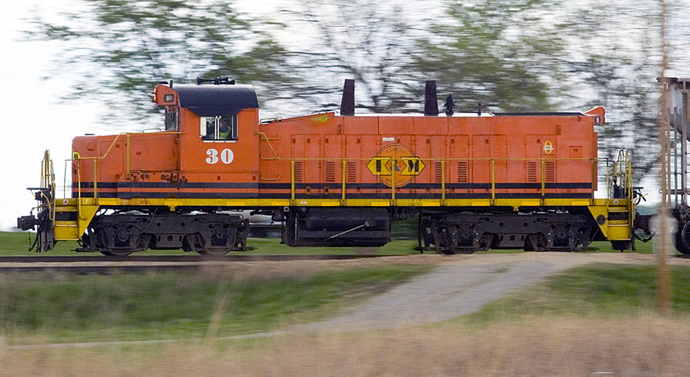 Side view of orange locomotive with switcher long hood and road-switcher short hood