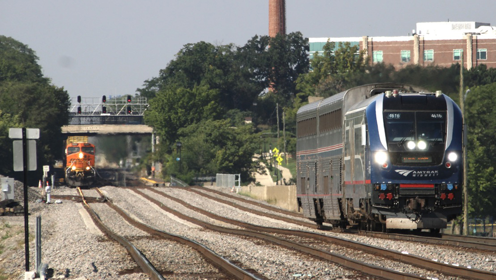 Short passenger train approaches with freight train in background