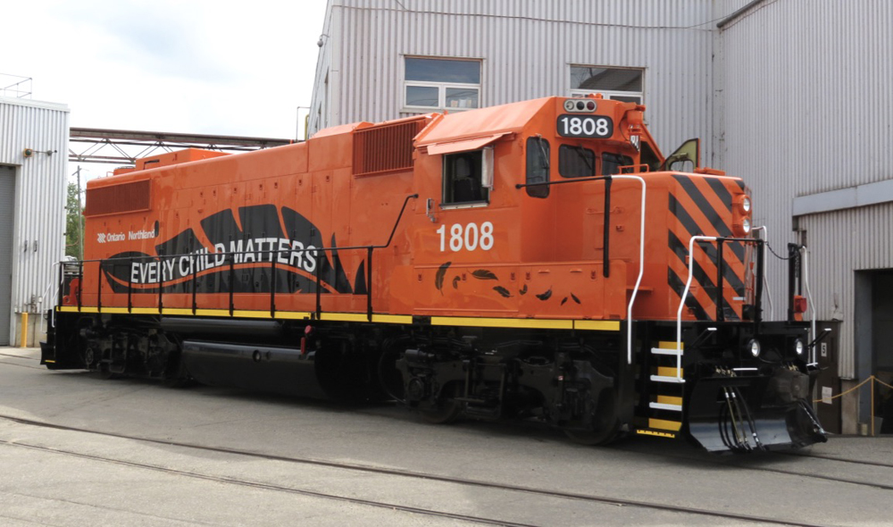 Orange locomotive with words "Every Child Matters" on black feather painted on long hood
