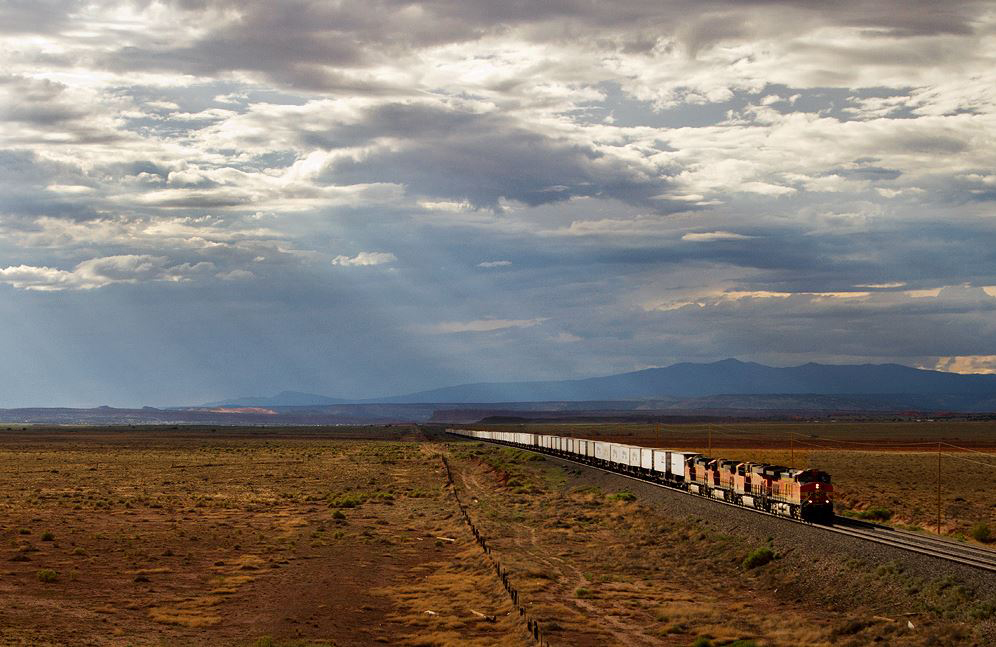Freight train in desert landscape beneath dramatic clouds
