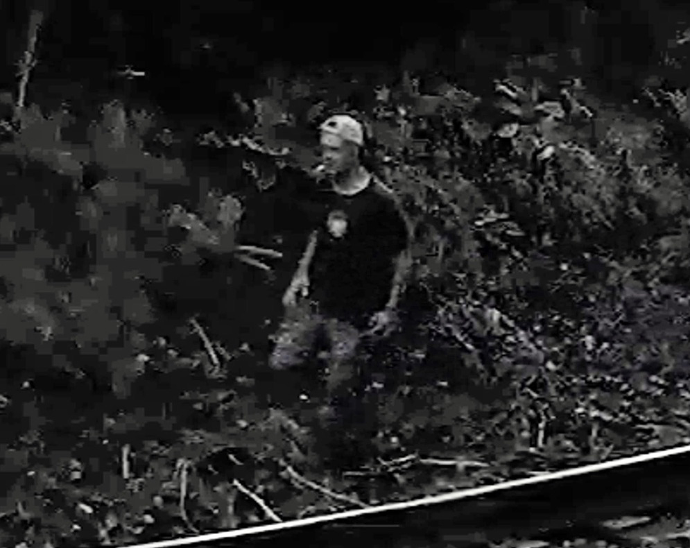 Black-and-white enlargement of video footage of man walking next to railroad tracks