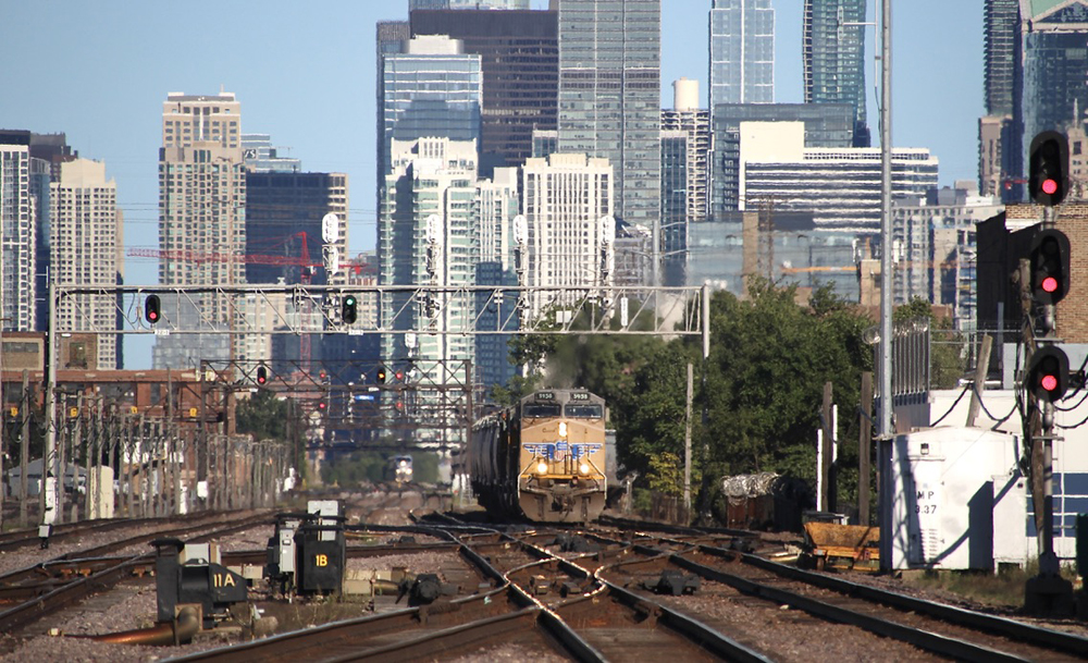 Freight train with yellow locomotive against Chicago skyline