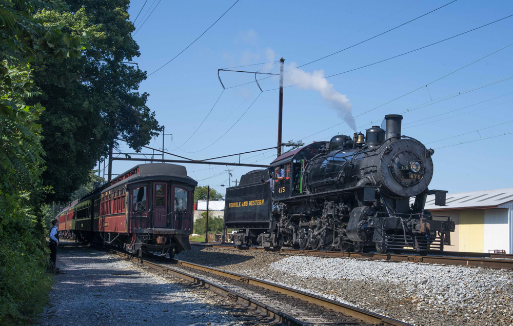 Steam locomotive on track next to vintage passenger car