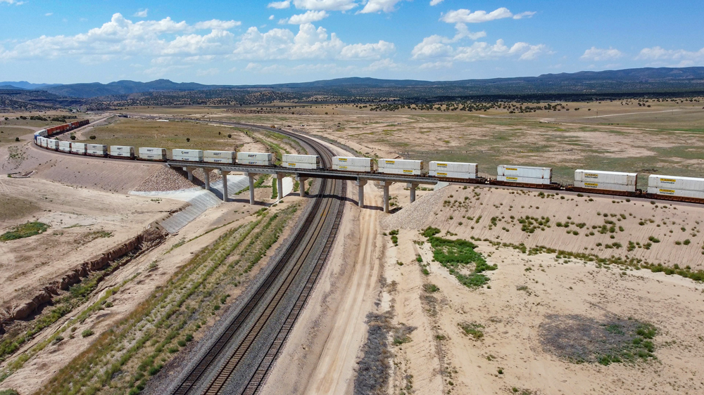 Train on bridge crossing over railroad tracks in desert landscape
