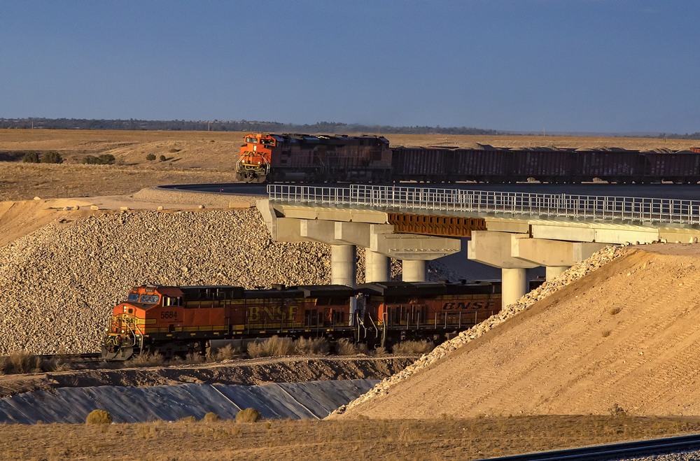 Train approaches bridge over railroad tracks as another train passes below