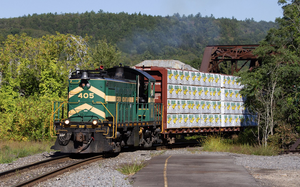 Green locomotives with yellow strip switching at industry