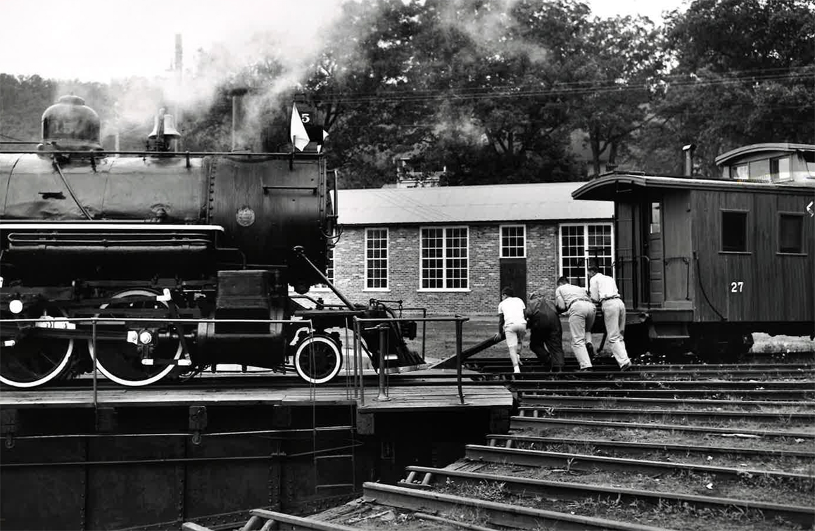 4 men pushing to turn locomotive on turntable