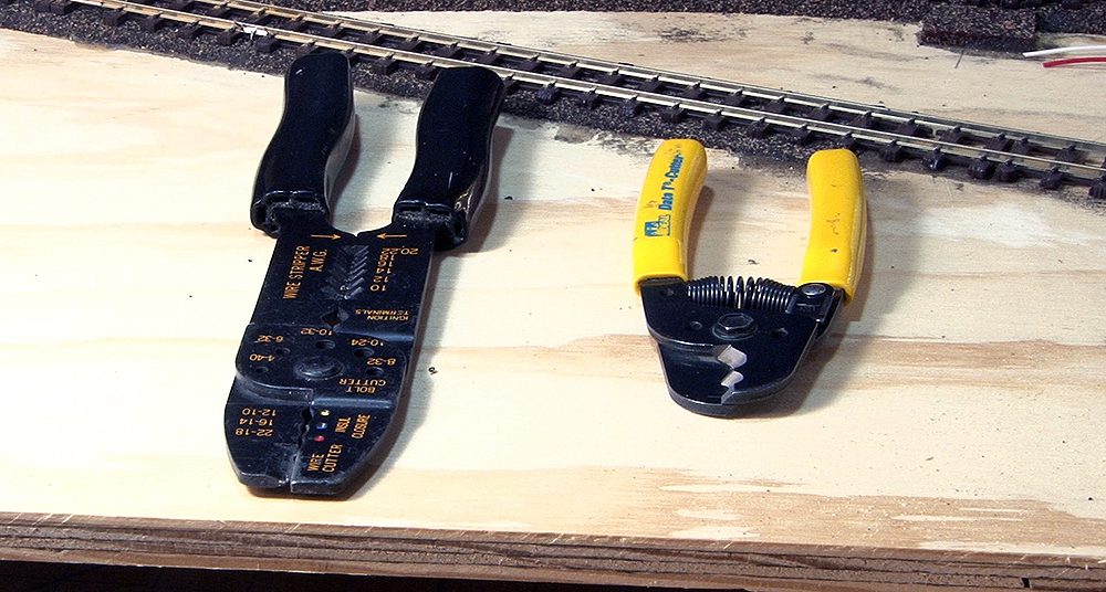 Two pairs of wire strippers, one large with black handles and one small with yellow handles