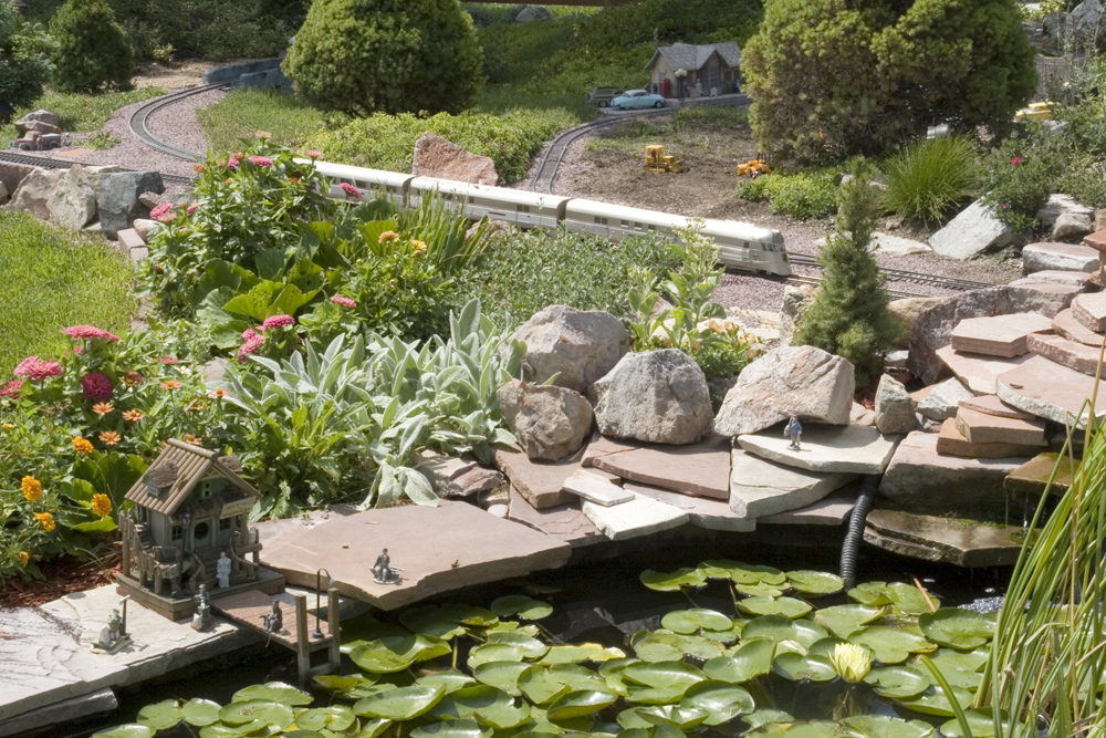 model locomotive on garden railway with a pond nearby