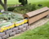 model yellow train exiting covered bridge