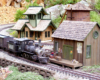 Freelance Colorado narrow-gauge branch line: model steam train approaches buildings