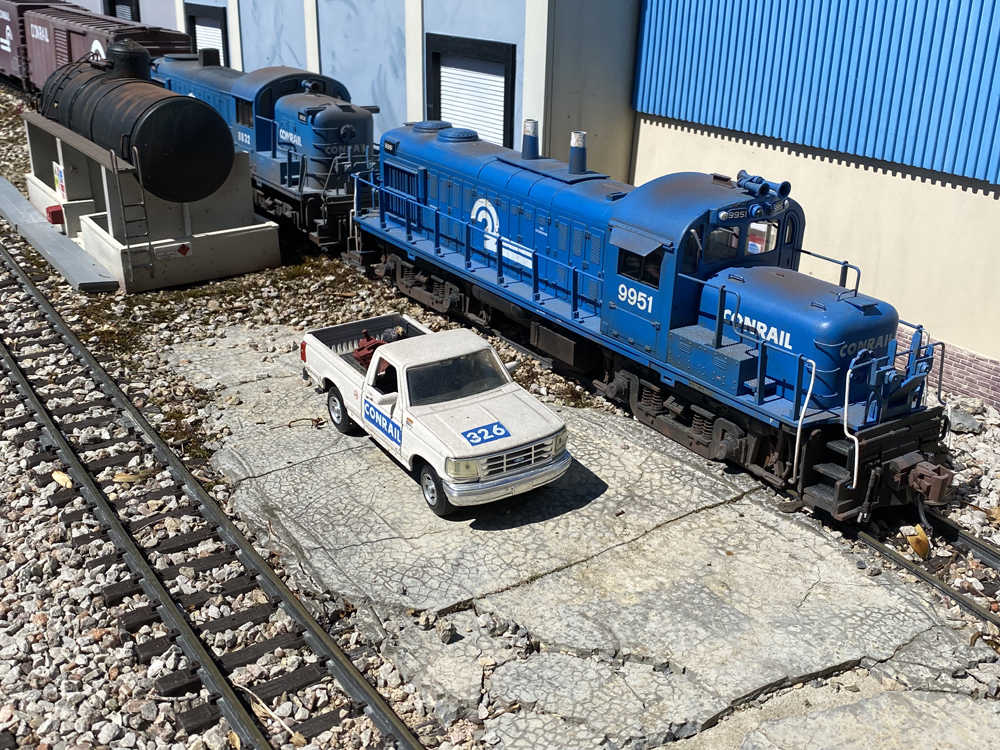 white model truck and blue model diesel locomotive
