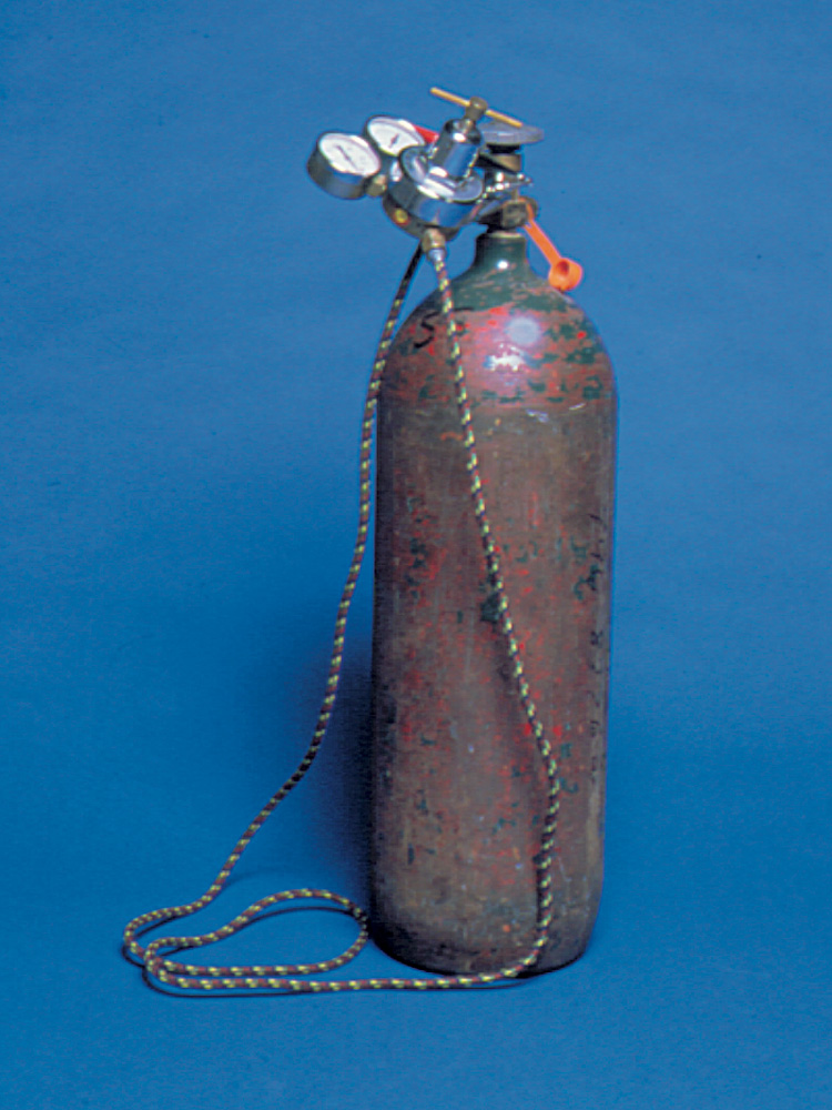 A rusty air tank with a regulator and air hose against a blue background