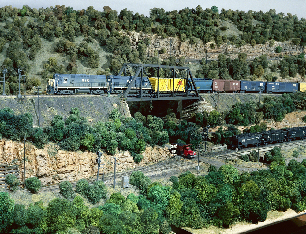 Photo of a train passing over a bridge with rocky outcroppings above and below