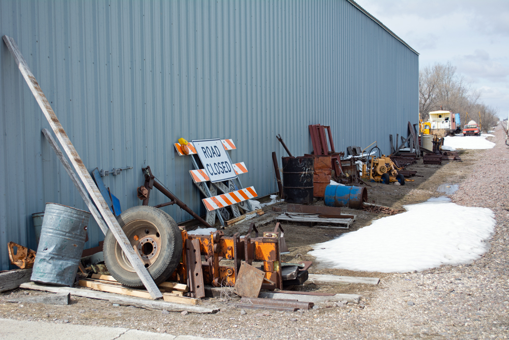 Tires, signs, barrels, and other objects next to the side of a building