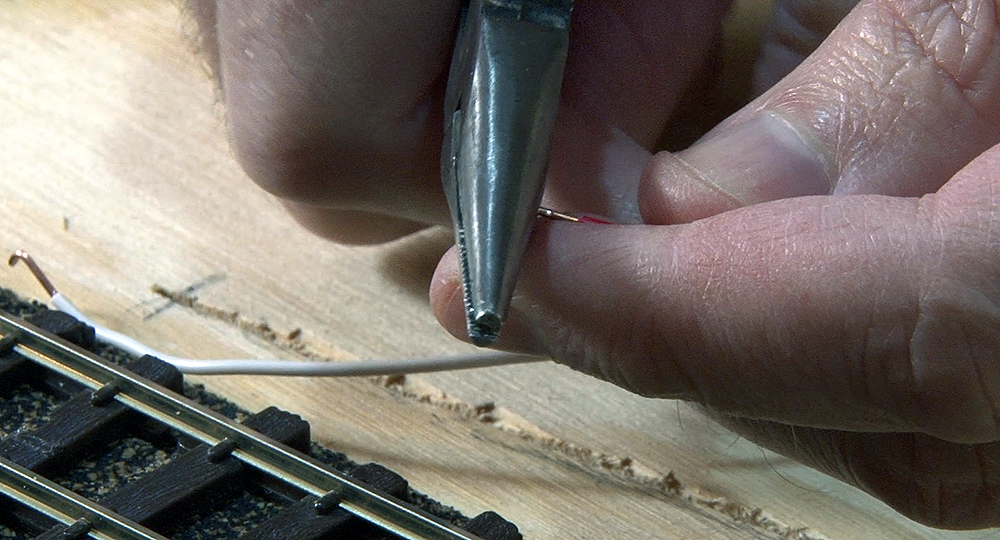 A air of needle-nose pliers being used to crush the tip of the wire.