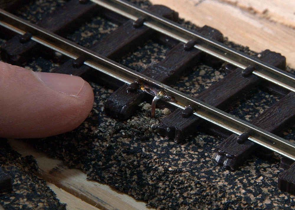 A finger being used to confirm the quality of the soldering.