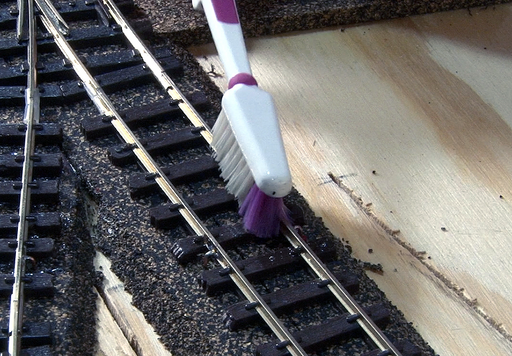 An old tooth brush being used to clean rails.