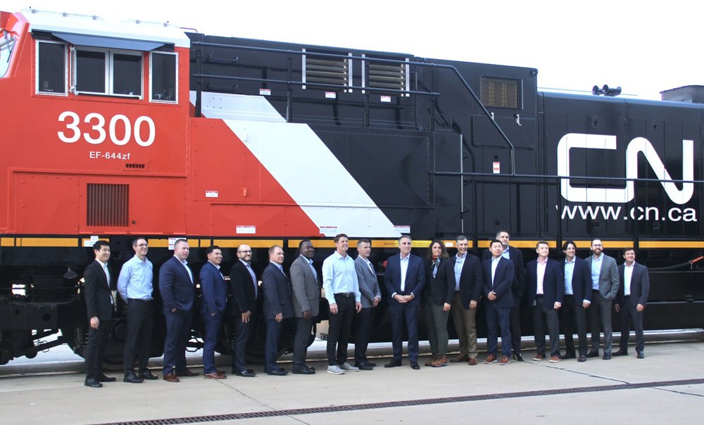 18 people standing in front of locomotive