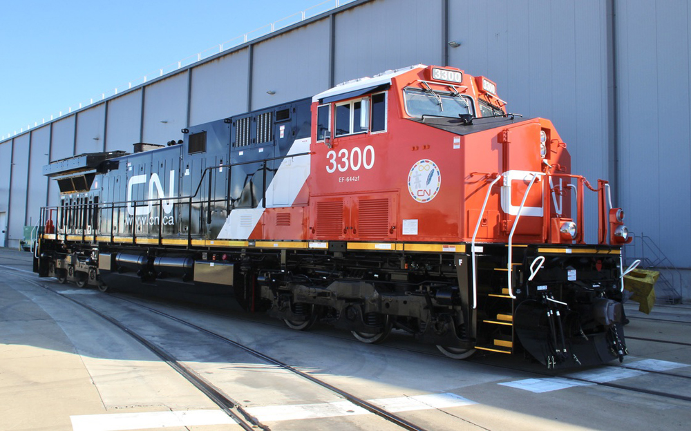 Red, white, and black locomotive outside factory