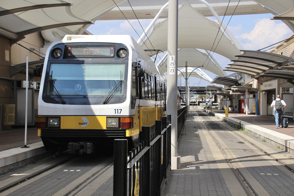 Light-rail train at end-of-line station with a departing train in the distance. Traveling Dallas-Fort Worth by rail.